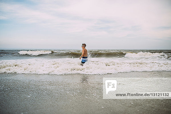 Junge steht im Meer gegen den Himmel am Strand