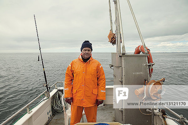 Front view of fisherman standing on fishing boat at sea