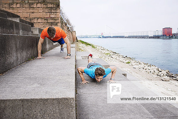 Determined male athletes doing push-ups on steps at beach