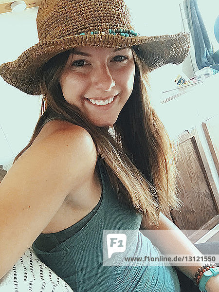 Nahaufnahme einer glücklichen Frau mit Hut  die im Wohnmobil sitzt
