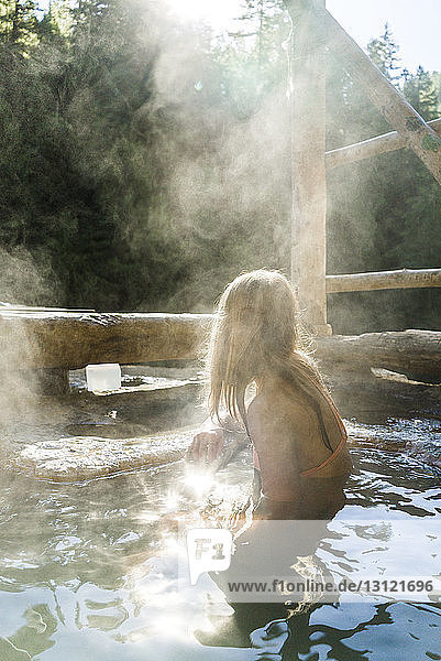 Woman wearing biking relaxing in hot spring at forest