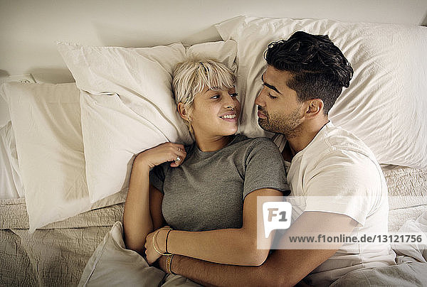 Draufsicht auf ein junges Paar  das sich zu Hause auf dem Bett ausruht