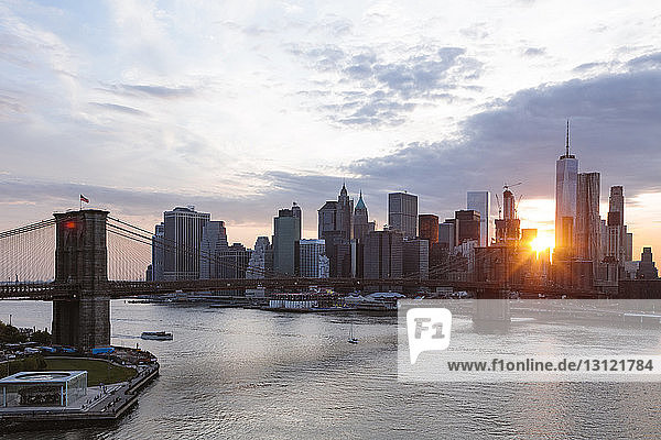 Brooklyn Bridge über den East River in New York City bei Sonnenuntergang