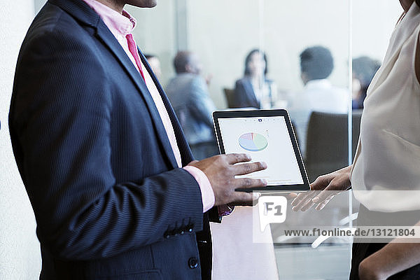 Geschäftsmann zeigt seinem Bürokollegen ein Tortendiagramm auf einem Tablet-Computer