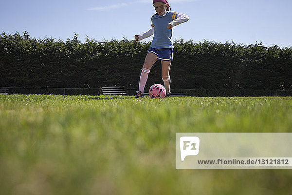 Mädchen übt Fussball auf einem Rasenplatz