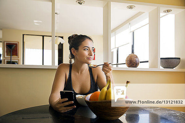 Nachdenkliche Frau frühstückt zu Hause auf dem Tisch