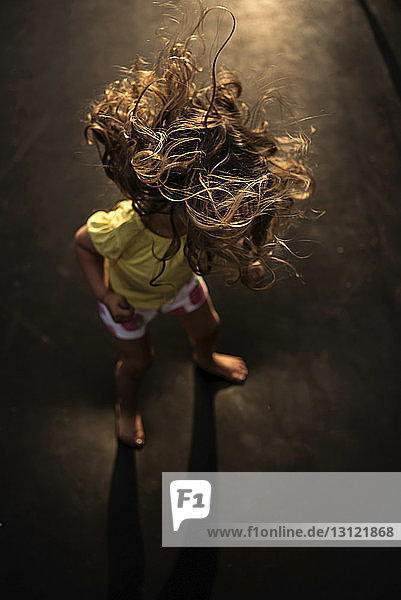 High angle view of girl with tousled hair standing on trampoline