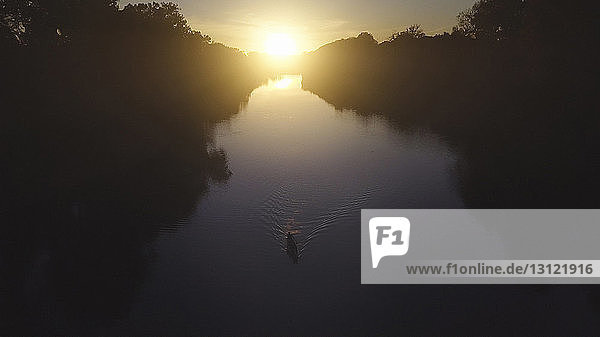 Hochwinkelaufnahme von Vater und Sohn beim Bootfahren auf dem See bei Sonnenuntergang