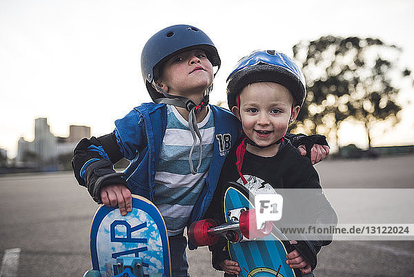 Porträt von niedlichen Jungen  die mit Skateboard auf dem Feld vor klarem Himmel stehen