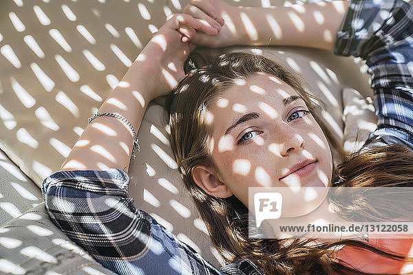 Porträt einer selbstbewussten Teenagerin  die sich zu Hause beim Korbschwingen entspannt