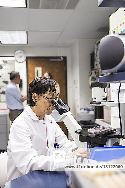 Senior female scientist using microscope in laboratory