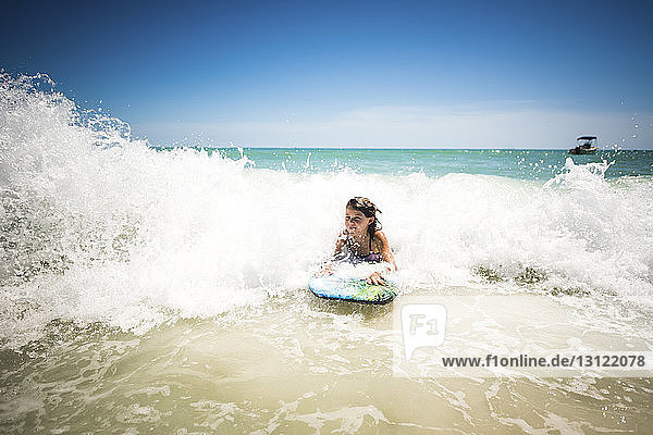 Girl surfing in sea against clear sky