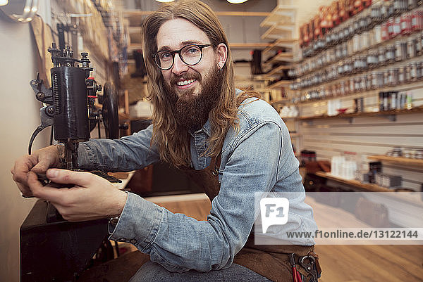 Porträt eines lächelnden Schuhmachers bei der Arbeit an der Nähmaschine in der Werkstatt