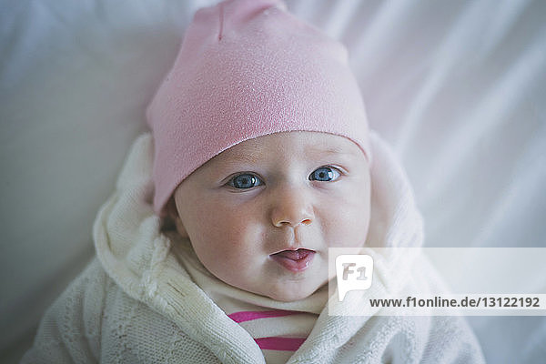 Portrait of baby in warm clothing lying on bed at home