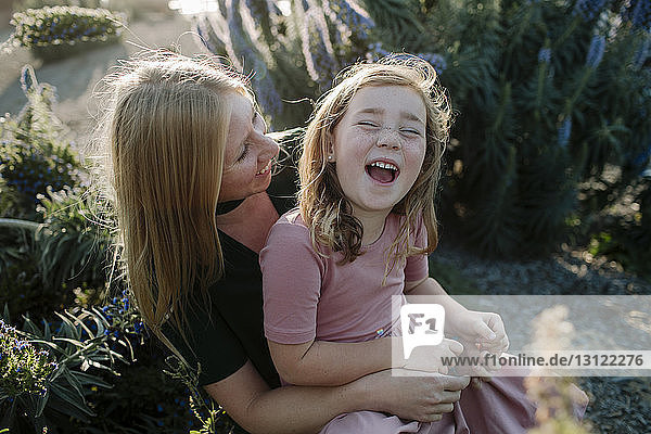 High angle view of happy mother and daughter sitting at park