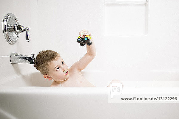 Junge spielt mit Spielzeug  während er zu Hause in der Badewanne badet