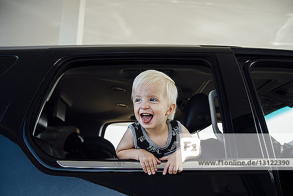 Glücklicher kleiner Junge schaut durchs Fenster  während er im Auto unterwegs ist