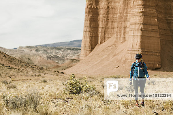Wanderin wandert in voller Länge in der Wüste gegen Felsformationen