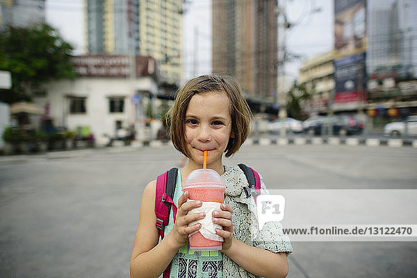 Porträt eines Mädchens  das im Stehen in der Stadt trinkt