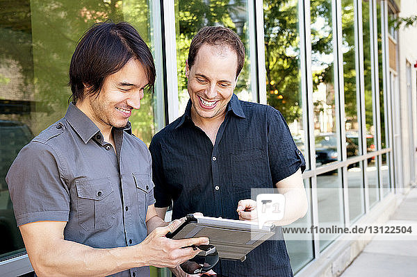 Male friends smiling while looking at tablet computer