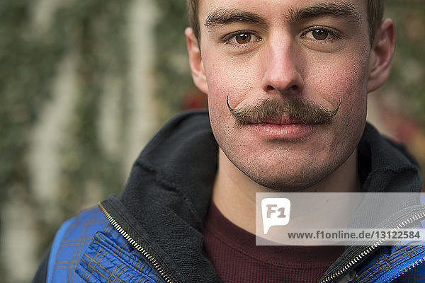 Close-up portrait of confident man with mustache at backyard