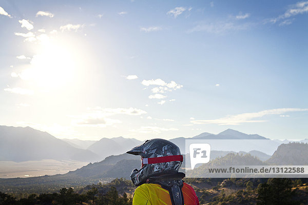 Schmutziger Radfahrer  der am sonnigen Tag Berge gegen den Himmel schaut