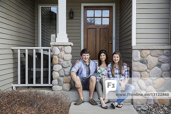 Portrait of happy family sitting at entrance