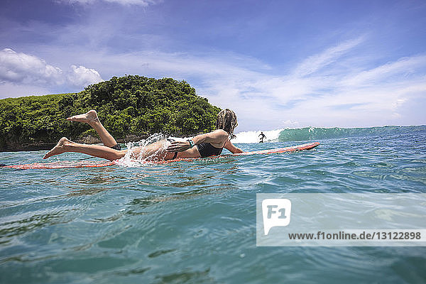 Freunde surfen auf dem Meer gegen den Himmel in Bali