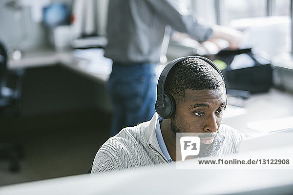 Hochwinkelansicht eines Geschäftsmannes am Desktop-Computer mit einem männlichen Kollegen im Hintergrund