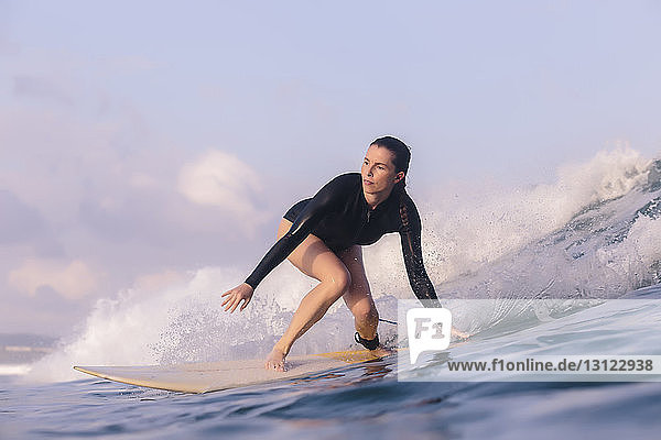 Low angle view of woman surfing in sea against sky