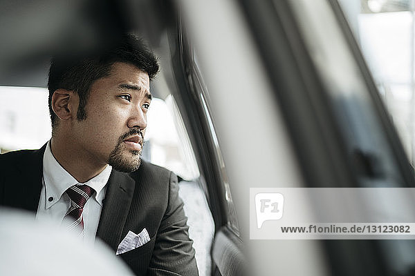 Thoughtful businessman looking through taxi window