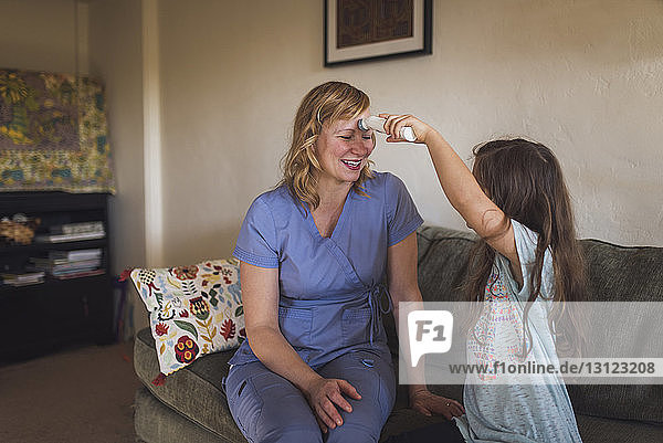 Mädchen gibt einer Ärztin eine Kopfmassage  während sie zu Hause auf dem Sofa sitzt