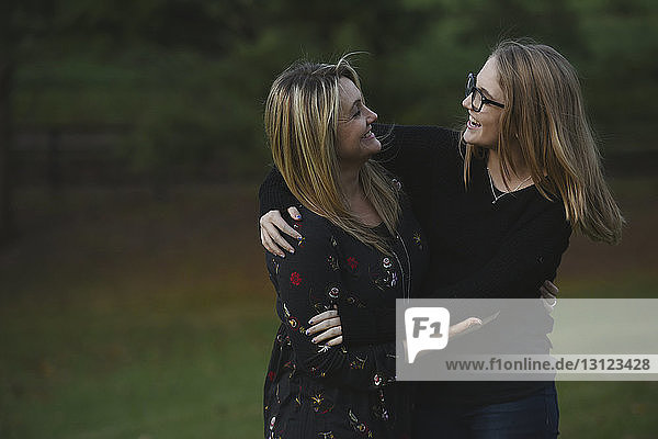 Glückliche Mutter und Tochter sehen einander an  während sie auf dem Hof stehen