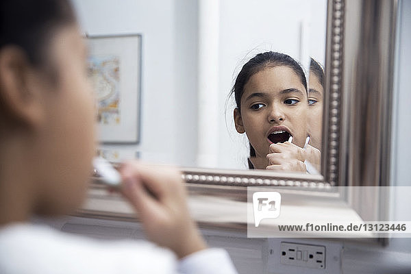 Reflection of girl in mirror brushing teeth