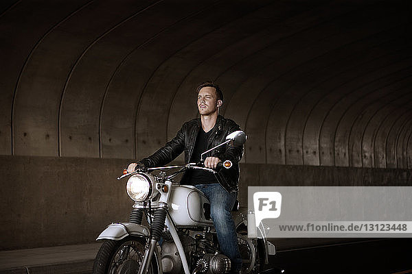 Motorrad fahrender Mann unter Brücke