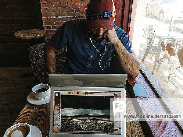Hochwinkelansicht eines Mannes  der einen Laptop-Computer benutzt  während er im Café sitzt