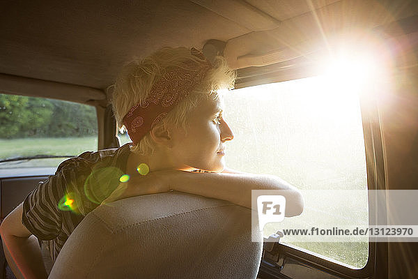 Thoughtful woman looking through car window on sunny day