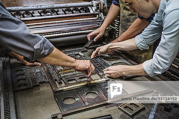 Arbeiter arrangiert Buchdruck an Maschinen in der Werkstatt