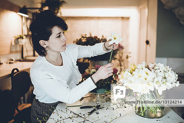 Seitenansicht eines Floristen  der Narzissen in einer Vase im Blumenladen arrangiert