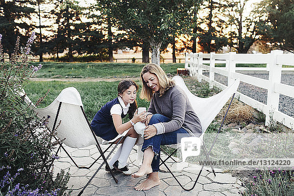 Daughter wearing school uniform while showing smart phone to mother at yard