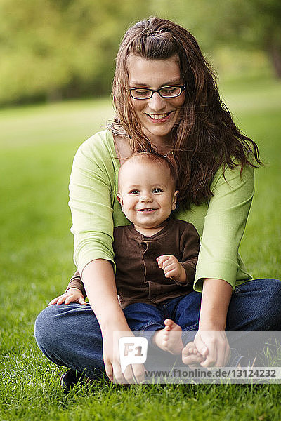 Mutter und Sohn sitzen zusammen auf einem Grasfeld