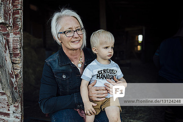 Grandmother with grandson sitting at barn