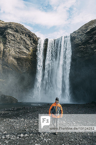 Mann läuft gegen den Wasserfall Skogafoss in Island