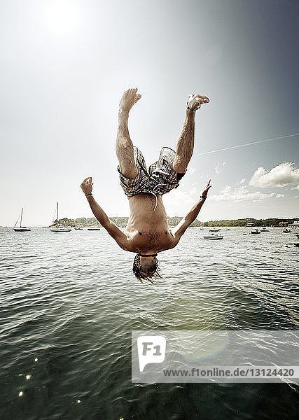 Carefree man diving into sea against sky