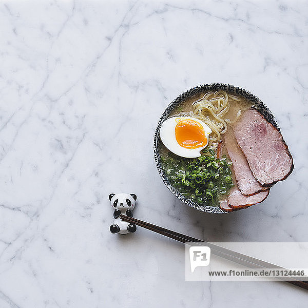 Hochwinkelansicht einer Ramen-Nudelsuppe mit Schweinefleisch in einer Schüssel auf der Theke serviert