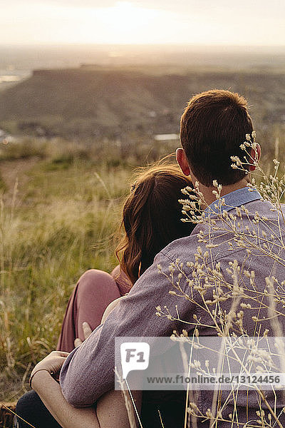Young couple looking at view while sitting on field