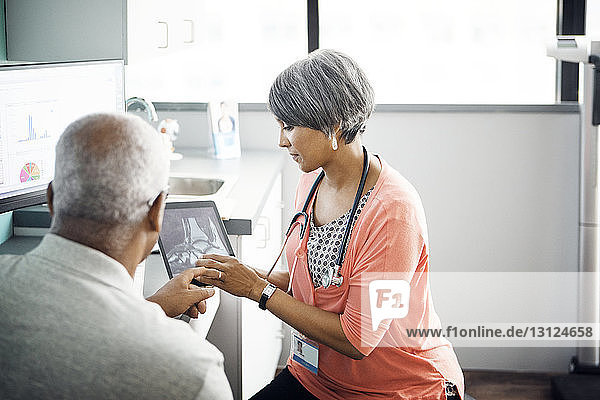 Female doctor explaining x-ray to patient on tablet computer in clinic