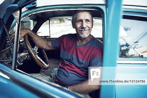 Man looking away while sitting in vintage car