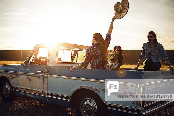 Friends enjoying in pick-up truck during sunset