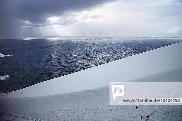 Szenische Ansicht des Meeres durch ein schneebedecktes Feld gegen den Himmel